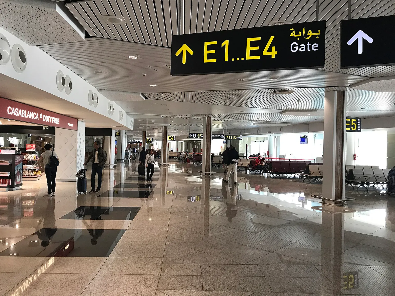 Zone d'embarquement du Terminal 1 de l'aéroport Mohammed V avec boutiques et panneaux des portes