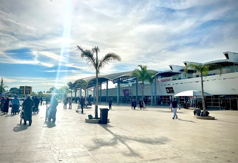 Façade du terminal de l'aéroport Mohammed V de Casablanca avec palmiers et parvis ensoleillé