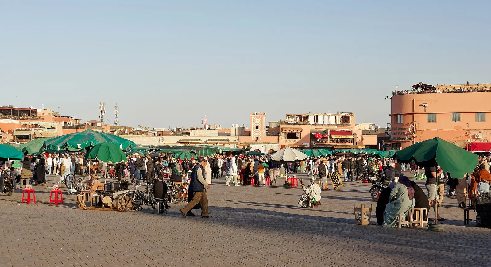 Place Jemaa el-Fna à Marrakech en fin d'après-midi, avec ses stands et la foule au loin