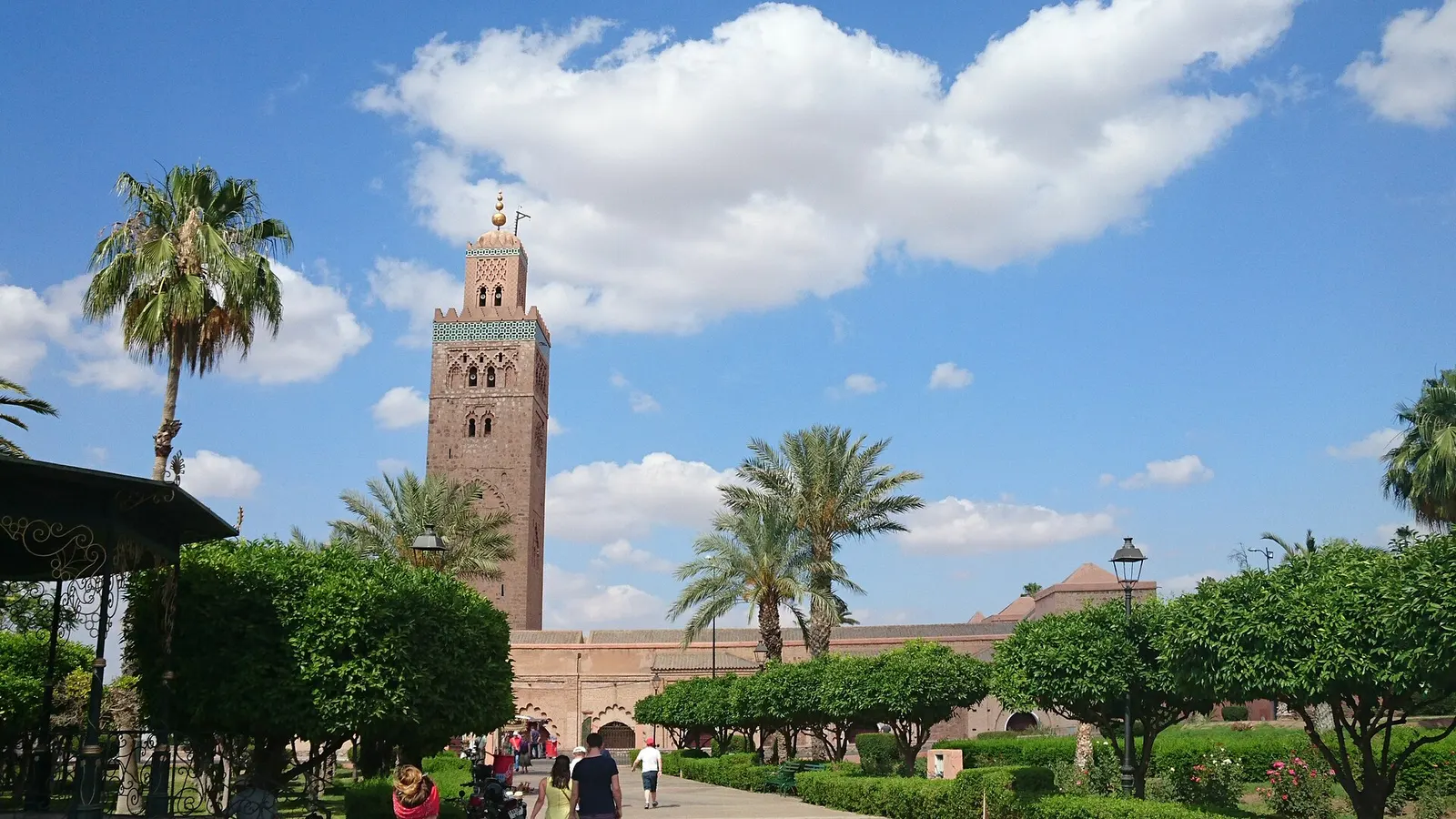 Minaret de la Koutoubia à Marrakech entre les palmiers et les jardins, sous un ciel bleu