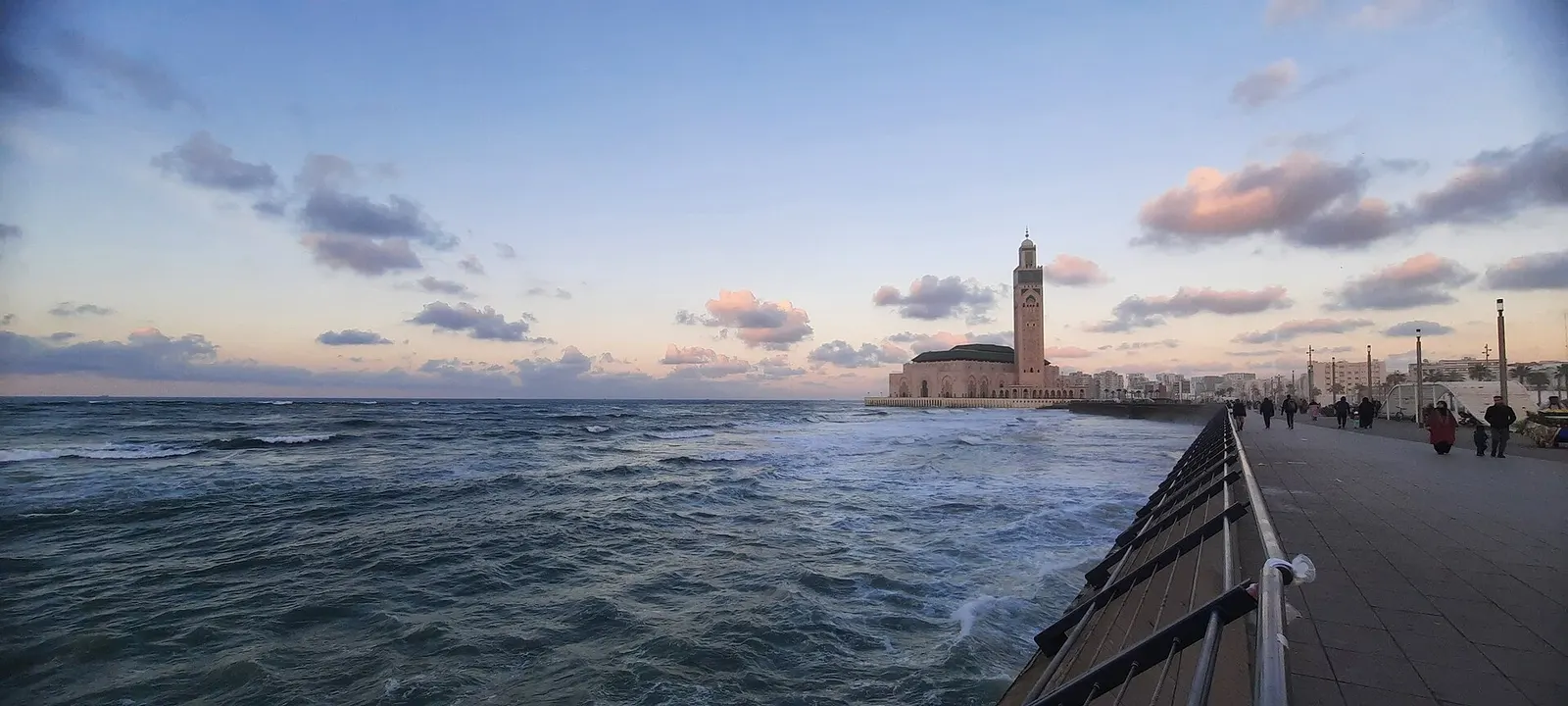 Oceanfront promenade in Casablanca with Hassan II Mosque on the horizon at dusk
